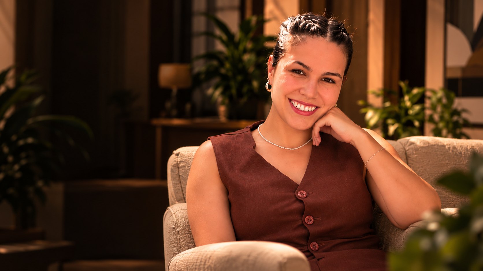 Ayla Camargo sorrindo, sentada em uma poltrona em um ambiente acolhedor